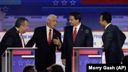 El exgobernador de Nueva Jersey, Chris Christie, el exvicepresidente Mike Pence, el gobernador de Florida, Ron DeSantis, y el empresario Vivek Ramaswamy conversan durante el receso del primer debate de las primarias presidenciales republicanas.