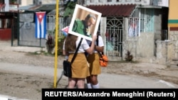 Estudiantes con una fotografía de Fidel Castro esperan en Buenaventura, Cuba, el 2 de diciembre de 2016, cuando una caravana con sus cenizas recorrió la isla hasta depositarlas en Santiago de Cuba.