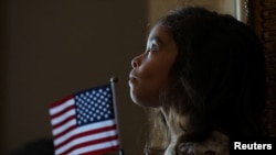 Un niño escucha el himno nacional durante la ceremonia de naturalización, en
Boston. Los cubanos ocuparon el quinto puesto en recibir la ciudadania de EEUU en 2023.