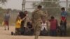 La inmigrante cubana Magdalena Ávila (arrodillada a la izquierda) y otras personas se emocionan después de cruzar ilegalmente la frontera sur de EEUU, el 9 de octubre de 2022 en Eagle Pass, Texas.
