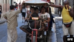 Varias personas esperan junto a una bicitaxi.