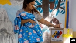 Una joven madre ejerce su derecho al voto en las presidenciales de este domingo, en Caracas, Venezuela. (AP/Cristian Hernandez)
