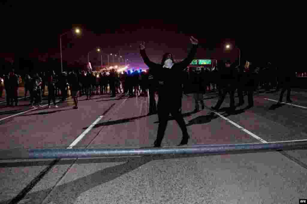 Un manifestante celebra tras haber ayudado a volcar una farola para cortar una carretera mientras varios activistas bloquean el tráfico en la autopista HWY 580 durante una protesta en Oakland, California, contra la elección del republicano Donald Trump como presidente de EEUU.  