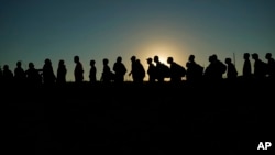 Migrantes que cruzaron el Río Grande y entraron a EEUU desde México hacen fila para ser procesados por la Oficina de Aduanas y Protección Fronteriza estadounidense. (AP/Eric Gay, File)