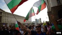 Un grupo de manifestantes ondean banderas de Bulgaria durante una protesta anti-gobierno en Sofía (Bulgaria).