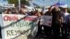 Migrantes llevarán rosas durante una marcha a agentes fronterizos
