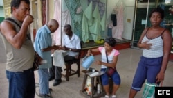 Varias personas toman café en el portal de una tienda, en La Habana, Cuba.
