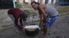 Residentes llevan una olla de caldosa para compartir con los vecinos después del paso del huracán Rafael por La Habana, el 7 de noviembre de 2024. (Foto AP/Ariel Ley)