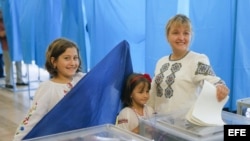 Una ucraniana con sus hijas deposita su voto en las urnas durante las elecciones presidenciales.