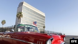 Un auto clásico pasa con una bandera de Estados Unidos frente a la embajada de ese país en La Habana.