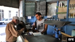 Un bodeguero vende productos racionados a un cliente en La Habana.