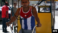 Un bicitaxista usa una camiseta con la bandera cubana por una calle de La Habana.