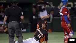 El jugador holandés Randolph Oduber (c) puntúa tras el error del cubano Frank Morejon (d) durante su partido del Clásico Mundial de Béisbol en Tokio, Japón.