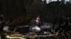 Una mujer cuelga un cartel de prohibido el paso en el sitio de una casa destruida por los incendios forestales de Maui en Kula, Hawai, el 13 de agosto de 2023.