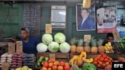 Dos jóvenes esperan la llegada de clientes en un agromercado en La Habana (Cuba) en 2016.