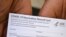 Un trabajador de la salud muestra una tarjeta de registro de vacunación contra el COVID-19 en el Centro de Salud Queens Care, en Los Ángeles, California, el 11 de agosto de 2021. Foto: Robyn Beck / AFP.