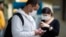 Pasajeros usando mascarillas como precaución contra el contagio del nuevo coronavirus usan sus teléfonos en el Aeropuerto Internacional de Sao Paulo, Brasil.