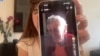 La activista cubana Carolina Barrero sostiene el teléfono con un video de Zoila Chávez, madre del escritor encarcelado José Gabriel Barrenechea.