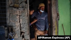 Emilio Román, padre de tres jóvenes prisioneros políticos por manifestarse el 11J, junto a su nuera María Carla Milan Ramos en su casa en el barrio La Güinera. ,