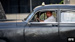 Un hombre maneja un viejo taxi particular en La Habana.