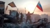 Dos miembros del Grupo Wagner, de Yevgeny Prigozhin, ondean el 20 de mayo una bandera rusa y del Grupo Wagner sobre un edificio en Bahmut, Ucrania. Prigozhin acusa a los militares rusos de no proporcionar municiones suficientes. (Servicio Prigozhin de Prensa vía AP).