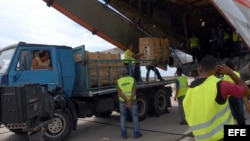 Trabajadores cubanos descargan paquetes de ayuda humanitaria de un avión IL-176, de la Federación Rusa, que arribó a Santiago de Cuba.