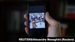Un hombre que no quiso ser identificado muestra en su teléfono al rapero contestatario Maykel Castillo El Osorbo. (REUTERS/Alexandre Meneghini)