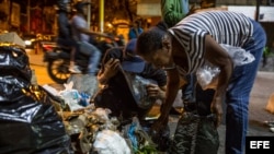 Varias personas buscan comida entre bolsas de basura, en Caracas, Venezuela.