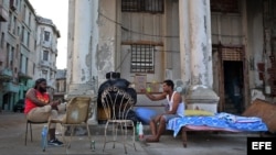 Dos hombres cuya vivienda fue severamente afectada por el huracán Irma conversan junto a sus pertenencias el jueves 21 de septiembre de 2017, en el malecón de La Habana (Cuba).