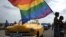 Un grupo de personas sostiene una bandera de la comunidad LGTBI.