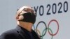 Un hombre se protege del coronavirus frente a un logo de los Juegos de Tokio. AP Photo/Koji Sasahara