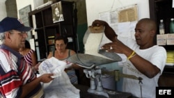 Un bodeguero despacha a un anciano el arroz que se distribuye mediante la libreta de racionamiento.