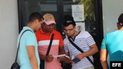 Tres cubanos revisan los documentos que les permiten comprar el boleto de avión, por 523,50 dólares cada uno, para viajar a México.