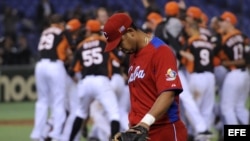 El jugador cubano Jose Abreu pasa delante del equipo holandés, que se encuentra celebrando su victoria tras imponerse a Cuba en el Clásico Mundial de Béisbol disputado en el estadio Tokyo (Japón).