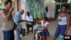 Varias personas toman café en el portal de una tienda.