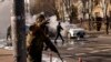 Soldados ucranianos toman posiciones en torno a una instalación militar mientras arden dos automóviles en una calle en Kiev, Ucrania, sábado 26 de febrero de 2022. (AP Foto/Emilio Morenatti)