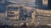 Un soldado ucraniano se desplaza entre los restos de un camión militar incendiado en una calle en Kiev, Ucrania, el sábado 26 de febrero de 2022. (AP Foto/Efrem Lukatsky)
