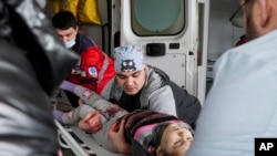 Rescatistas ucranianos socorren a una menor que fue herida en Mariupol, al este de Ucrania.