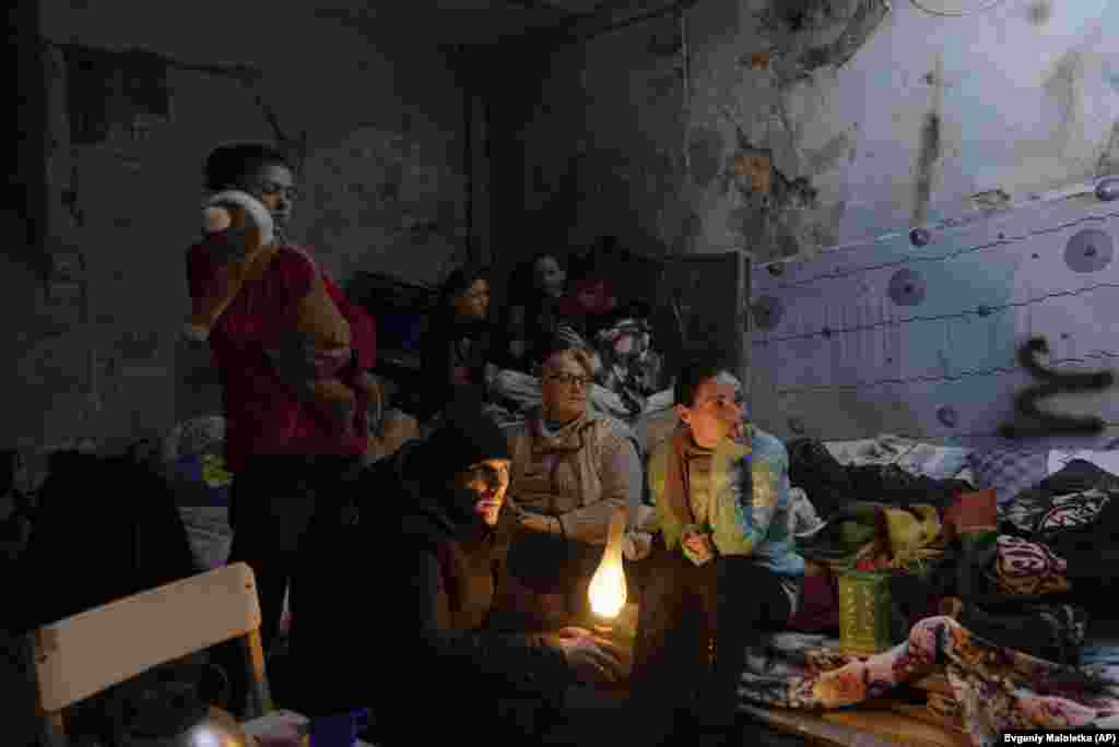 Alumbradas con una lámpare de querosene, varias personas esperan el día en un refugio de Mariúpol (Ucrania) el 6 de marzo.