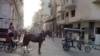Un carretón con un caballo y un bicitaxi circulan por una calle de La Habana, Cuba.