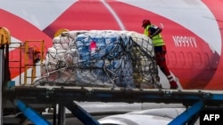 Un trabahjador descarga paquetes de ayuda humanitaria para venezolanos en el Aeropuerto Internacional Hato, en Willemstad, Curazao.