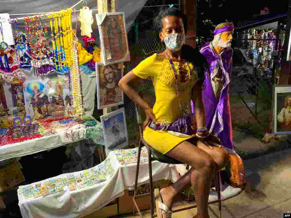 Una vendedora de imágenes religiosas espera a los clientes durante la procesión de San Lázaro,  en El Rincón, La Habana, Cuba, el 17 de diciembre de 2020. (Foto de ADALBERTO ROQUE / AFP)
