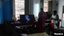 Trabajadores en un taller de reparaciones en La Habana, Cuba, escuchan un discurso de Miguel Díaz-Canel transmitido en la televisión cubana.