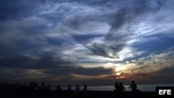 Varias personas descansan al atardecer en el muro del malecón de La Habana. Foto Archivo
