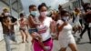 Una mujer con un niño en brazos marcha frente al Capitolio de La Habana durante una manifestación contra Miguel Díaz-Canel en La Habana, el 11 de julio de 2021. (Adalberto Roque/AFP).