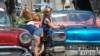 Una turista posa para una foto en La Habana Vieja. Al fondo, uno de los carruajes que pasean a los visitantes extranjeros.