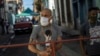Hombres montan guardia en una reja que corta el acceso a su vecindario en cuarentena por coronavirus, en La Habana, para mantener alejados a los que no viven allí. (AP/Ramon Espinosa)