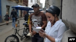 Una mujer se conecta a internet desde su celular en una calle de La Habana.