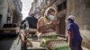 Una mujer que usa una máscara para frenar la propagación del nuevo coronavirus mira su teléfono móvil mientras viaja triciclo en La Habana. (AP Foto/Ramón Espinosa)