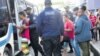 Miembros de la Unidad de Protección de menores trasladan a los cubanos que estaban acampados junto a sus padres en Port-of-Spain. Foto Guardian.